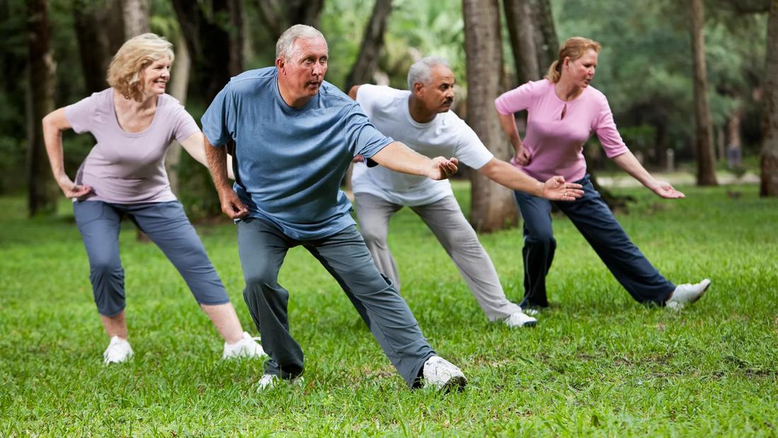 A group practising tai chi outdoors in a park