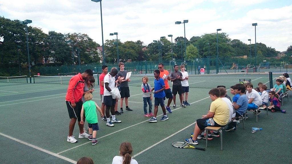 Coach running a junior tennis session on a park court